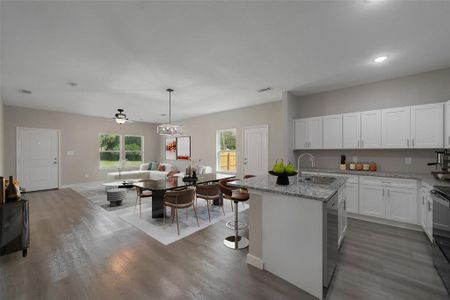 Kitchen with white cabinetry, hardwood / wood-style floors, a kitchen island with sink, and sink