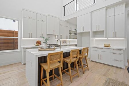 Kitchen with white cabinets, an island with sink, a breakfast bar, sink, and light hardwood / wood-style floors