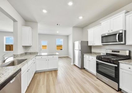 The kitchen has stainless steel appliances and plank flooring.