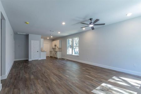 Unfurnished living room featuring ceiling fan and dark hardwood / wood-style floors