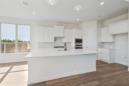 Kitchen with white cabinets, sink, stainless steel appliances, and a kitchen island with sink