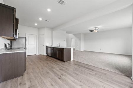 Kitchen with dark brown cabinets, sink, ceiling fan, and light hardwood / wood-style floors