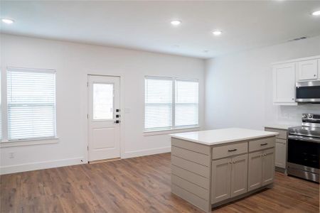 Kitchen featuring dark wood-type flooring, gray cabinets, appliances with stainless steel finishes, tasteful backsplash, and a kitchen island