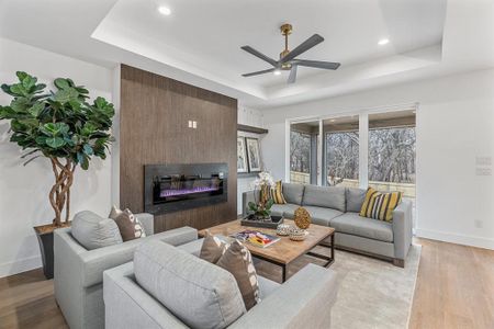 Living room featuring a raised ceiling, light hardwood / wood-style flooring, and a large fireplace