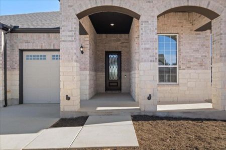 Spacious front entryway surrounded by a brick and stone exterior with upgraded uplighting.