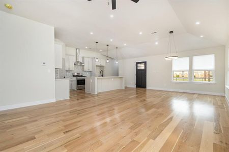 Unfurnished living room with lofted ceiling, light wood-type flooring, visible vents, and ceiling fan