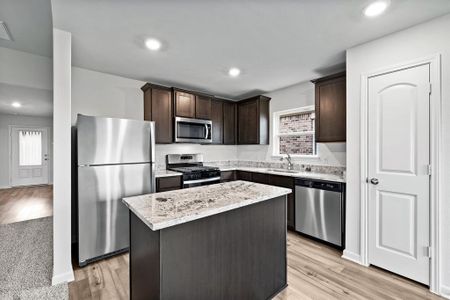 Kitchen featuring stainless steel appliances, a kitchen island, and light wood-type flooring