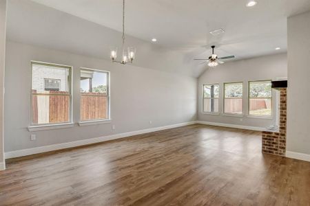 Unfurnished living room with plenty of natural light, hardwood / wood-style flooring, and ceiling fan with notable chandelier