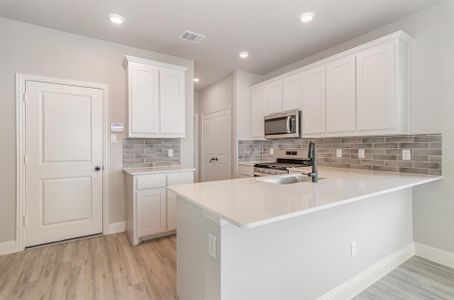 Kitchen with kitchen peninsula, white cabinetry, sink, and appliances with stainless steel finishes