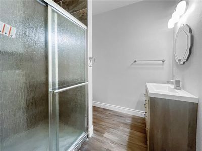 Bathroom featuring vanity, hardwood / wood-style floors, and a shower with door