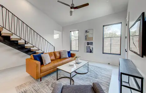 Living room with high vaulted ceiling, ceiling fan, stairway, and baseboards