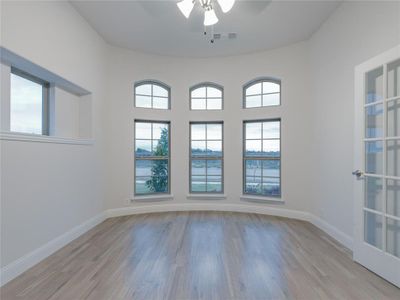 Unfurnished room featuring a wealth of natural light, ceiling fan, a water view, and light hardwood / wood-style floors