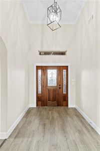 Foyer entrance with an inviting chandelier, light hardwood / wood-style floors, and crown molding