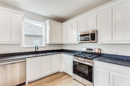 Kitchen featuring sink, light hardwood / wood-style flooring, white cabinetry, and appliances with stainless steel finishes