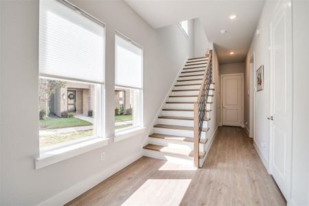 The foyer has a large coat closet and there is additional storage under the stairs.  The door in the background leads to the rear entry garage.  This home has luxury vinyl plank flooring in the entrance and all living areas.