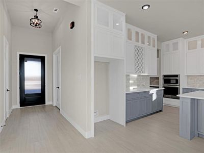 Kitchen featuring backsplash, hanging light fixtures, and white cabinets