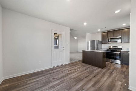 Kitchen with dark brown cabinets, a kitchen island, dark hardwood / wood-style floors, and stainless steel appliances