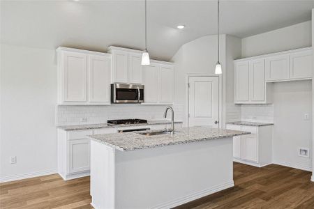 Kitchen featuring vaulted ceiling, dark hardwood / wood-style floors, light stone countertops, decorative backsplash, and white cabinets