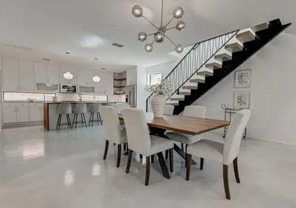 Dining area featuring finished concrete flooring, stairs, visible vents, and a chandelier