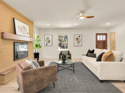 Living room with a fireplace, light wood-type flooring, and ceiling fan