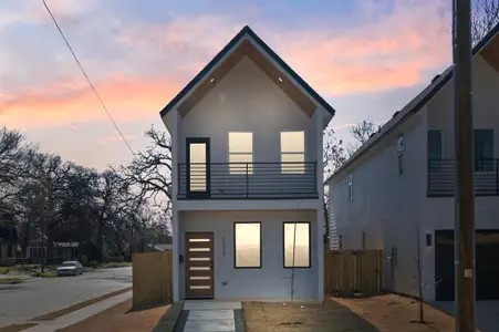 Back of property at dusk with a balcony, fence, and stucco siding