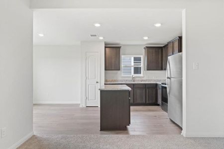 Kitchen featuring dark brown cabinets, stainless steel appliances, a kitchen island, and light hardwood / wood-style floors