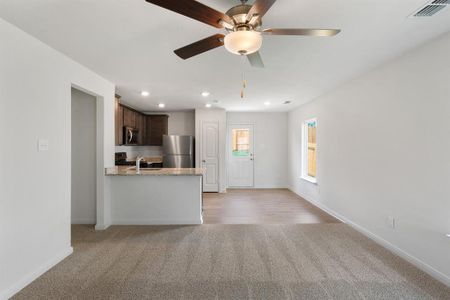 Unfurnished living room with ceiling fan, light colored carpet, and sink