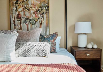 Bed with pink and tan linens and side table with a white lamp