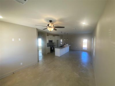 Kitchen featuring concrete flooring, range with electric stovetop, a kitchen island, white cabinetry, and ceiling fan