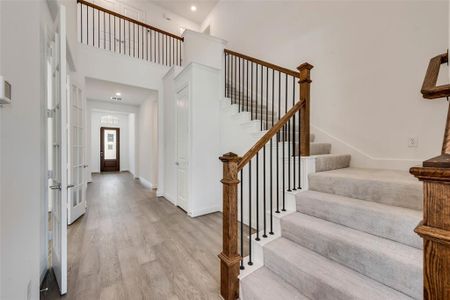 Foyer entrance with wood-type flooring, french doors, and a towering ceiling