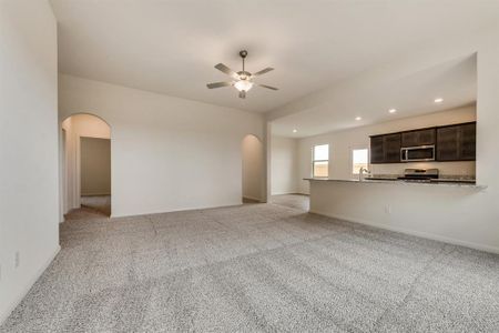 Unfurnished living room featuring ceiling fan and light colored carpet