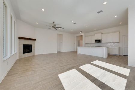 Unfurnished living room featuring ceiling fan and a tile fireplace