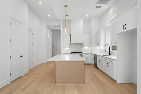 Another view of the impressive island kitchen with stylish pendant lighting and high-end finishes. (Photo is of a previously completed home which may have upgraded/alternative finishes.)