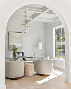 Living room with coffered ceiling, beamed ceiling, light hardwood / wood-style flooring, and an inviting chandelier