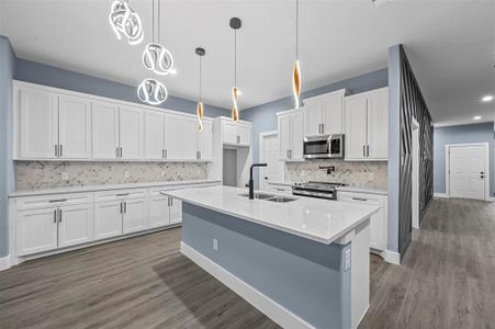 Kitchen featuring decorative light fixtures, dark hardwood / wood-style flooring, appliances with stainless steel finishes, sink, and white cabinets