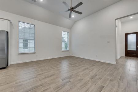 Unfurnished living room featuring ceiling fan, light hardwood / wood-style floors, and lofted ceiling