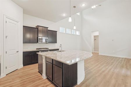 Kitchen featuring hanging light fixtures, sink, an island with sink, appliances with stainless steel finishes, and dark brown cabinetry