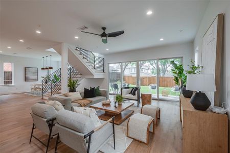 Living room with ceiling fan and hardwood / wood-style floors. It connects to a big patio and yard.