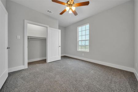 Unfurnished bedroom with ceiling fan, a closet, and carpet