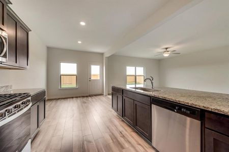 Kitchen featuring ceiling fan, sink, light hardwood / wood-style flooring, stainless steel appliances, and light stone countertops