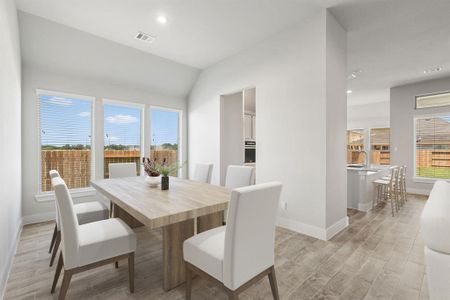 Craft enduring memories with loved ones around the table! This roomy dining area boasts stylish flooring, personalized paint, and is conveniently situated next to the family room and kitchen, fostering an open and inclusive ambiance. Sample photo of completed home with similar floor plan. As-built interior colors and selections may vary.