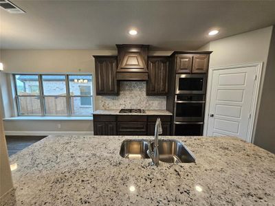 Maple slate colored cabinets, Colonial White granite counters, and decorative mosaic tile backsplash