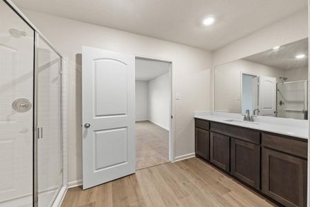 Full bathroom featuring a stall shower, vanity, baseboards, and wood finished floors