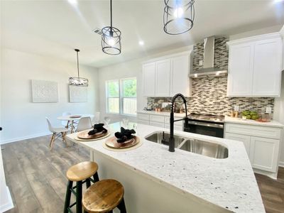 Kitchen featuring tasteful backsplash, pendant lighting, wall chimney exhaust hood, hardwood / wood-style flooring, and sink