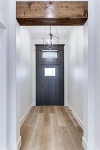 Foyer with an inviting chandelier, light wood-style flooring, ornamental molding, and baseboards