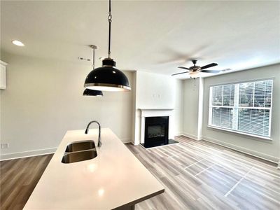 Kitchen with sink, ceiling fan, decorative light fixtures, and light hardwood / wood-style flooring