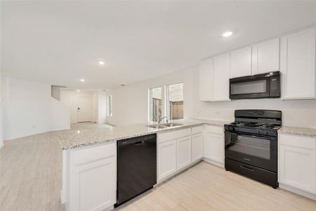 Kitchen with white cabinetry, sink, black appliances, and kitchen peninsula