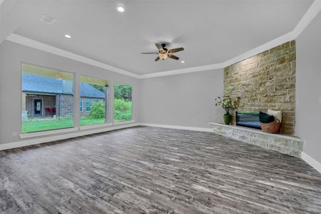 Unfurnished living room with a fireplace, ornamental molding, dark wood-type flooring, and ceiling fan