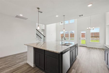 Kitchen with stainless steel dishwasher, sink, wood-type flooring, and an island with sink