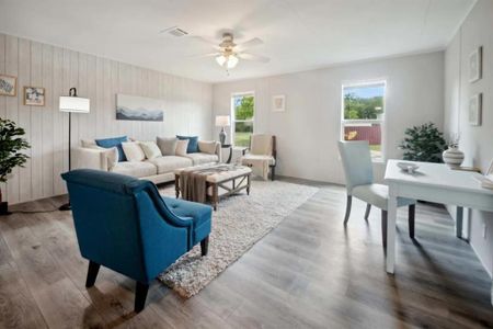 Living room with hardwood / wood-style flooring, wooden walls, ceiling fan, and a wealth of natural light